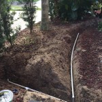 Laying line and sprinkler head in lava rock trench.